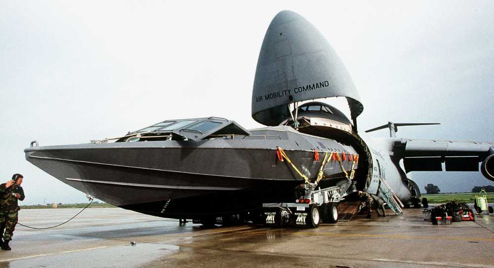 A C-5 Galaxy transport aircraft from the 349th Airlift Wing of the U.S. Air Force uses a multi-wheel tractor/transporter to load a MkVSOC boat.