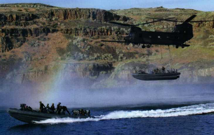 The 11-meter rigid inflatable boat (RHIB) belonging to the SBT-12 boat team conducted vertical transfer training at Moses Lake in Washington State using the Marine External Air Transport System (MEATS) on the MH-47G Chinook helicopter. When the helicopter hoists the speedboat for deployment, the crew members are in the cabin and go directly to the boat along the zip line; when evacuating, the speedboat is hung on the helicopter with a steel cable, and the crew members use a ladder to enter the helicopter. 